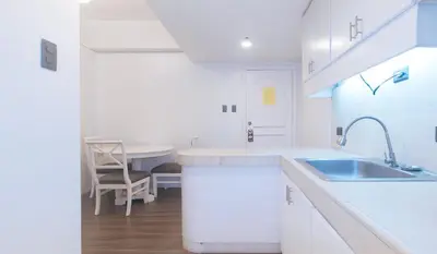 a white kitchen with a sink and a table at RedDoorz at MPT Suites in Manila