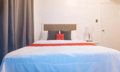 a bedroom with a large bed with a red pillow at RedDoorz at MPT Suites in Manila