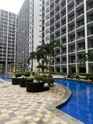 a swimming pool in front of a large building at Obetskie's Haven Condotel in Manila