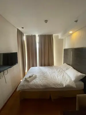 a bedroom with a white bed with a flat screen tv at A Venue Residences 9133 in Manila