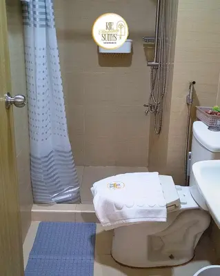 a bathroom with a shower with a toilet and a shower curtain at RJE Staycation Suites Mall of Asia near Airports in Manila