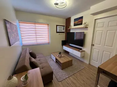 a living room with a couch and a flat screen tv at Berkeley Suites, Silang Cavite in Silang