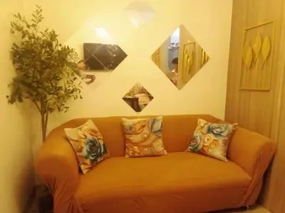an orange couch in a living room with a mirror at Staycation Near MOA, SMX Convention Center, DFA in Manila