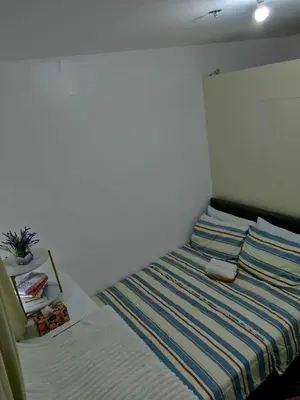 a bedroom with a bed with a striped blanket at South Residence Condo Las Pinas, Manila in Manila