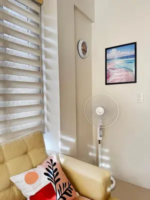 a living room with a couch and a fan at Chic Unit with Balcony - Free wifi & netflix across Naia Terminal 3 Airport in Manila