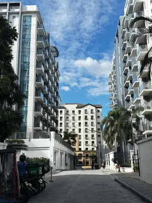 a street with two tall buildings and palm trees at Chic Unit with Balcony - Free wifi & netflix across Naia Terminal 3 Airport in Manila