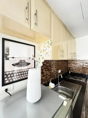 a kitchen with a sink and a vase with flowers on a counter at Chic Unit with Balcony - Free wifi & netflix across Naia Terminal 3 Airport in Manila