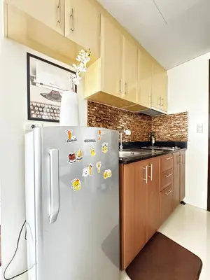 a kitchen with a refrigerator and wooden cabinets at Chic Unit with Balcony - Free wifi & netflix across Naia Terminal 3 Airport in Manila