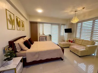 a large bedroom with a bed and a couch at Chic Unit with Balcony - Free wifi & netflix across Naia Terminal 3 Airport in Manila