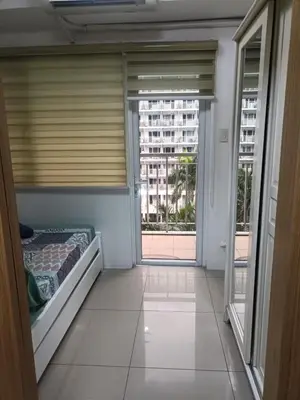 a room with a bed and a view of a building at Shell Residences in Manila