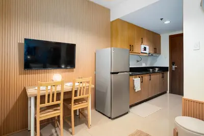 a kitchen with a refrigerator and a table with chairs at Brand New Unit Shell Residences 1BR Near MOA NAIA in Manila