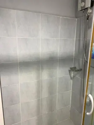 a shower in a bathroom with a tile wall at MOA Staycation - by Marites in Manila
