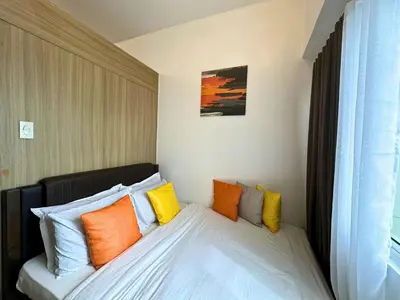 a bed with colorful pillows on it in a room at Cozy Luxe Stay 55 inch 4k Ultra TV and Amenity View in Manila