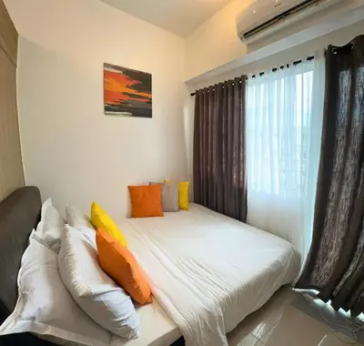 a bedroom with a bed with pillows and a window at Cozy Luxe Stay 55 inch 4k Ultra TV and Amenity View in Manila