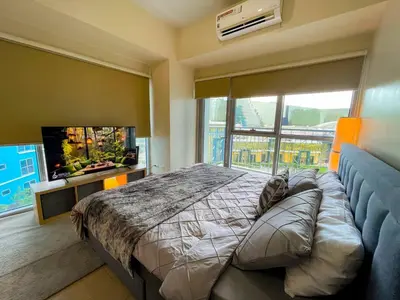 a bedroom with a large bed and a large window at Sophisticated City Escape Steps from Solaire & City of Dreams in Manila