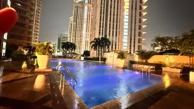 a large swimming pool in a city with tall buildings at AdahkuMaya Luxury Suites in Manila