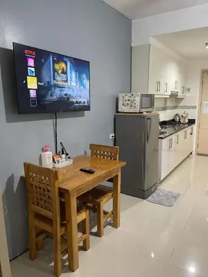 a kitchen with a wooden table and a television on the wall at Joyce Condo unit Sea Residences in Manila