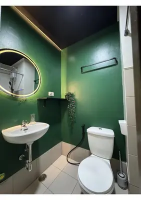 a green bathroom with a toilet and a sink at Cozy Urban Staycation Condo Unit in Manila