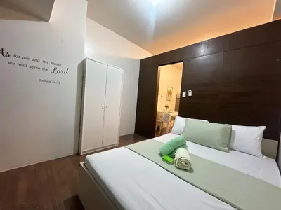 a bedroom with a large bed with a large headboard at Air Residences 3 by AG in Manila