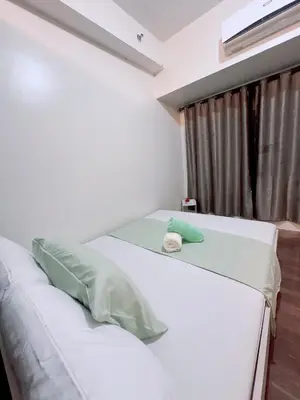 two white beds in a room with a window at Air Residences 3 by AG in Manila