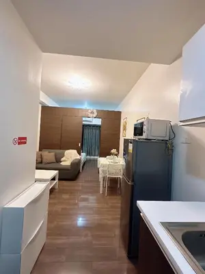 a kitchen with a refrigerator and a living room at Air Residences 3 by AG in Manila