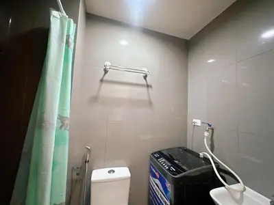 a bathroom with a toilet and a green shower curtain at Air Residences 3 by AG in Manila