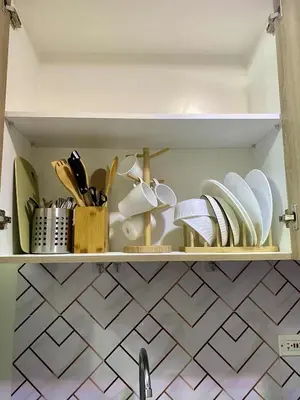 a shelf with plates and utensils in a kitchen at LiCa Place 2 in Manila