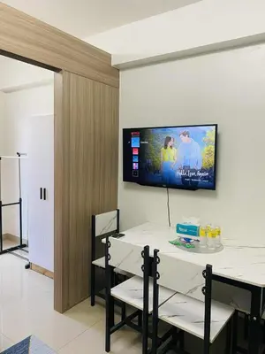 a dining room with a table and a tv on the wall at LiCa Place 2 in Manila