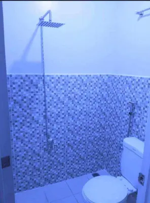 a bathroom with a toilet and a blue tiled wall at Eurica transient Inn in Manila