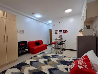 a living room with a red couch and a kitchen at CocaCola Studio Unit McKinley in Manila