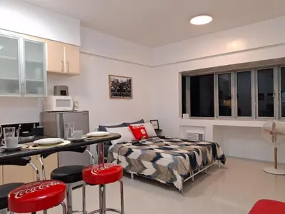 a bedroom with a bed and a table and chairs at CocaCola Studio Unit McKinley in Manila