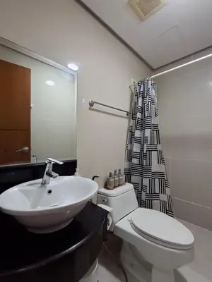 a bathroom with a sink and a toilet and a shower curtain at CocaCola Studio Unit McKinley in Manila