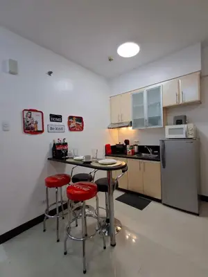 a kitchen with a table and two chairs and a refrigerator at CocaCola Studio Unit McKinley in Manila