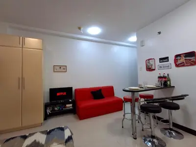 a living room with a red couch and a table at CocaCola Studio Unit McKinley in Manila