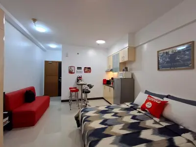 a living room with a bed and a red couch at CocaCola Studio Unit McKinley in Manila