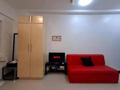 a living room with a red couch and a cabinet at CocaCola Studio Unit McKinley in Manila
