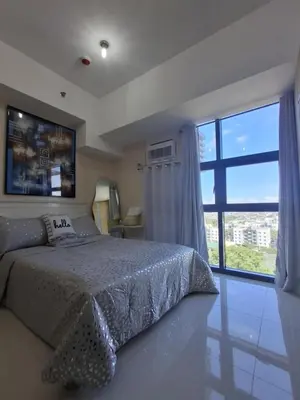 a bedroom with a bed and a large window at Cozy Studio Unit McKinley Hill in Manila