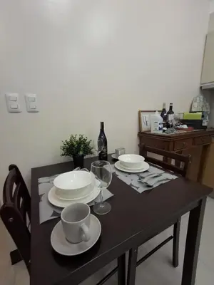 a dining room table with plates and wine glasses at Cozy Studio Unit McKinley Hill in Manila