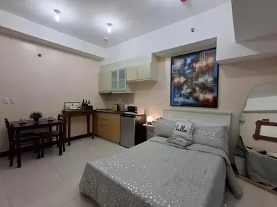 a living room with a bed and a kitchen at Cozy Studio Unit McKinley Hill in Manila