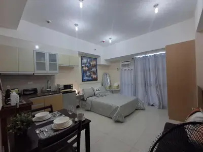 a large living room with a bed and a kitchen at Cozy Studio Unit McKinley Hill in Manila