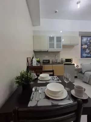 a kitchen with a table with plates and wine glasses at Cozy Studio Unit McKinley Hill in Manila