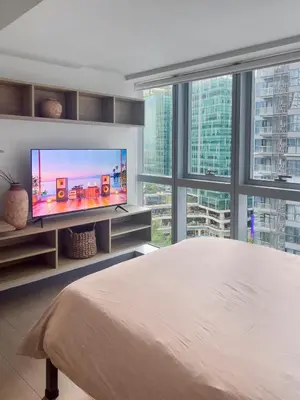 a bedroom with a large bed and a flat screen tv at Modern 1BR BGC Uptown View in Manila