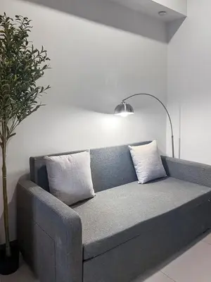 a gray couch with two pillows in a living room at Modern 1BR BGC Uptown View in Manila