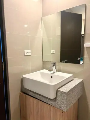 a bathroom with a white sink and a mirror at Modern 1BR BGC Uptown View in Manila