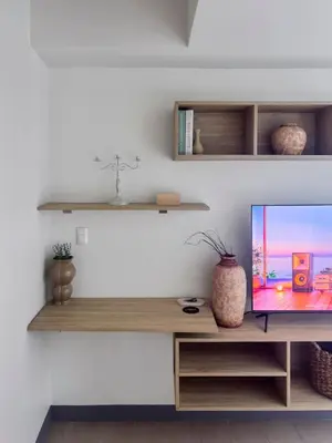 a living room with a tv on a wooden shelf at Modern 1BR BGC Uptown View in Manila