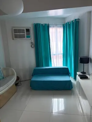 a bedroom with a bed and a window with blue curtains at UrbanhavenCozyFamilybedroom in Manila