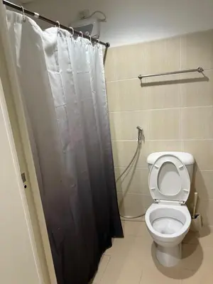 a bathroom with a toilet and a shower curtain at UrbanhavenCozyFamilybedroom in Manila