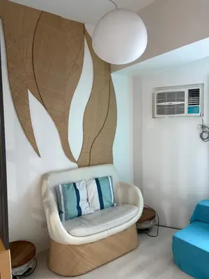 a living room with a white chair and a wall at UrbanhavenCozyFamilybedroom in Manila