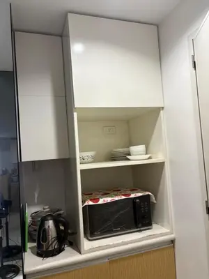 a white cabinet with a microwave in a kitchen at UrbanhavenCozyFamilybedroom in Manila