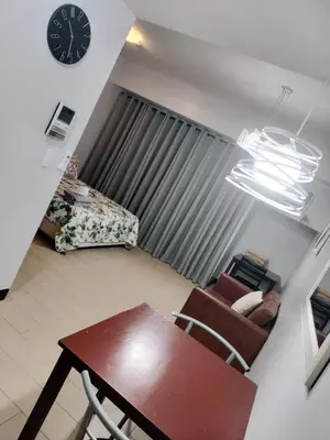 a living room with a table and a clock on the wall at Rqui Rooms Near Airport in Manila